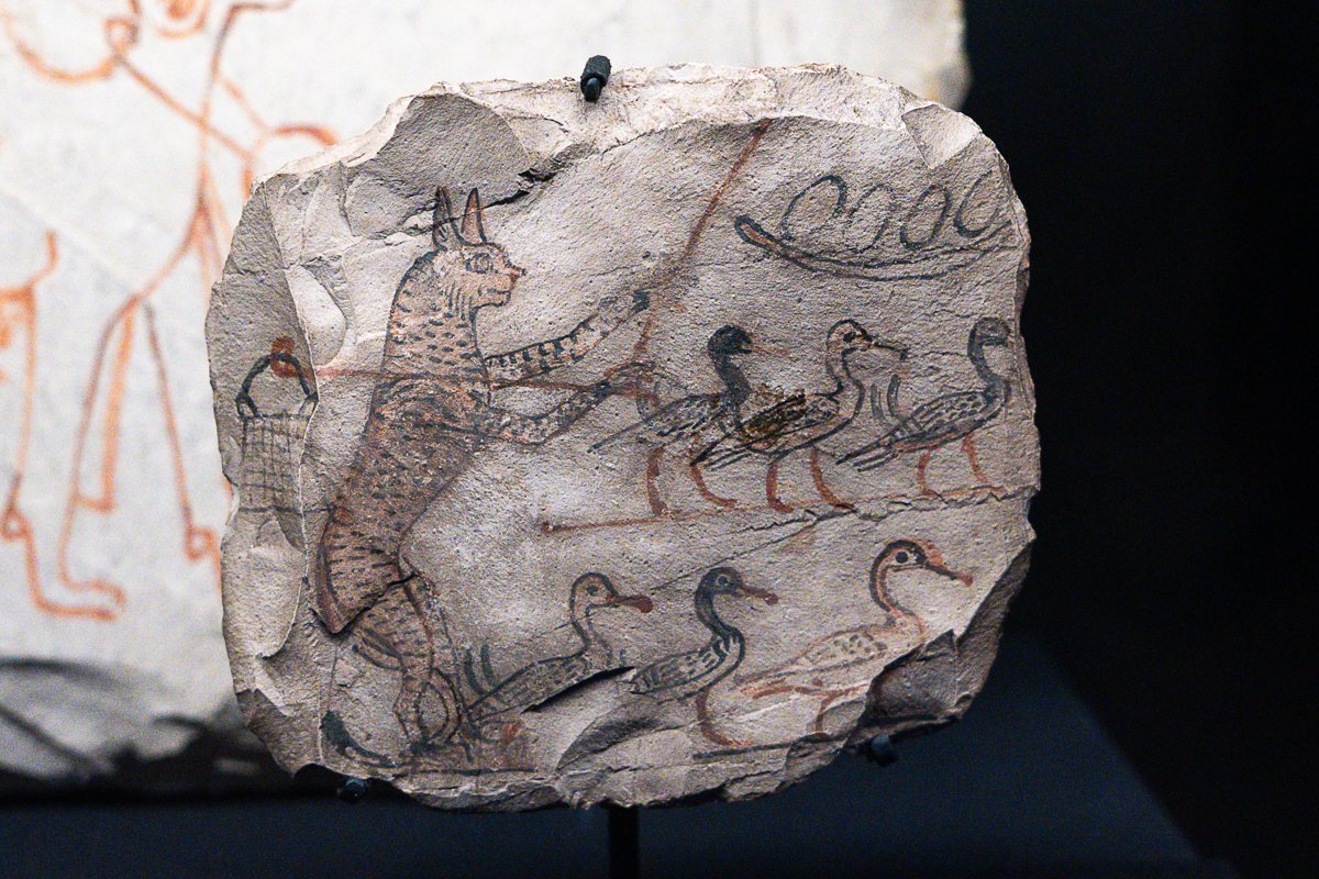 A limestone ostracon: animals in ink — a hyena and a lion among birds, a sly commentary on the pharaoh.