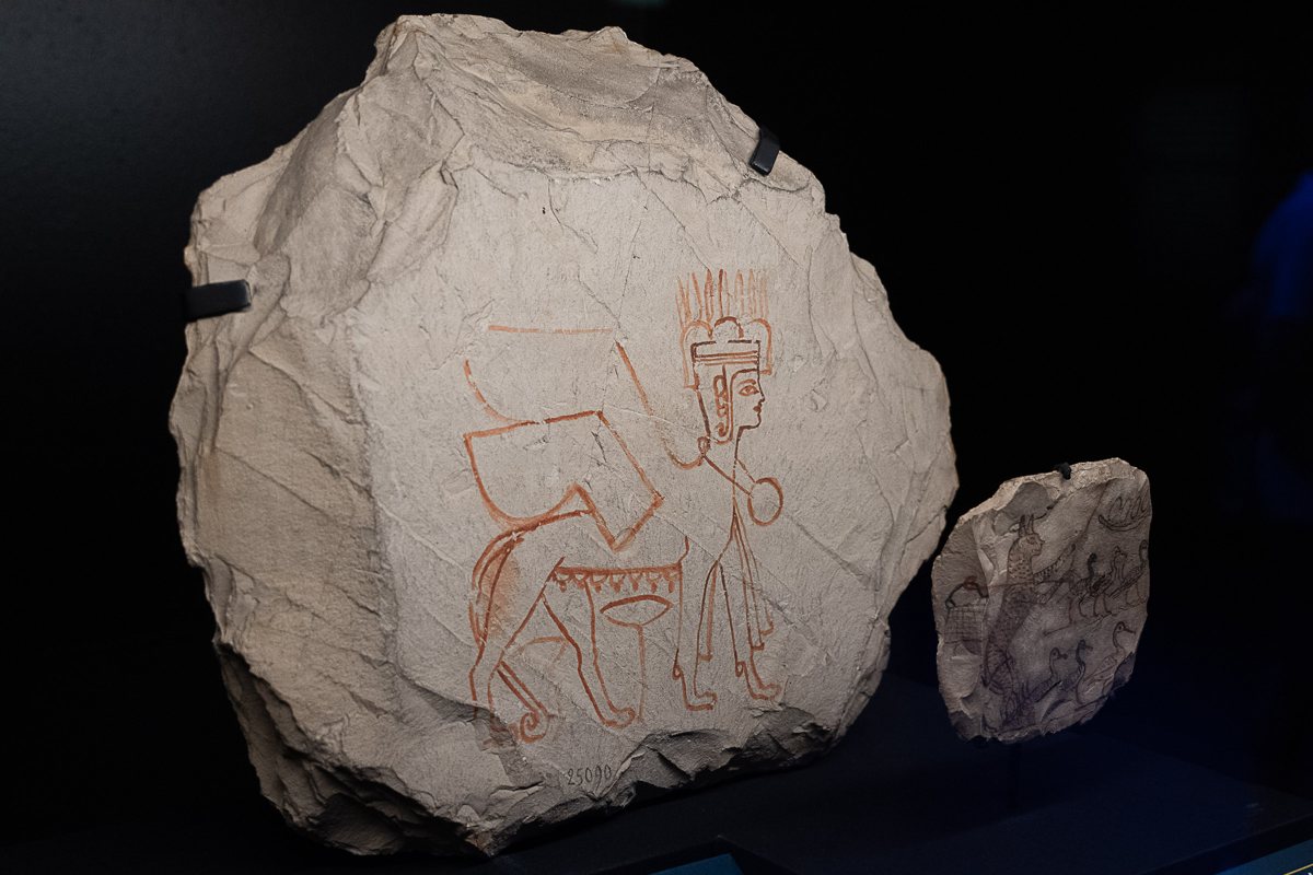 A limestone ostracon sketched in red ink: a winged female sphinx.